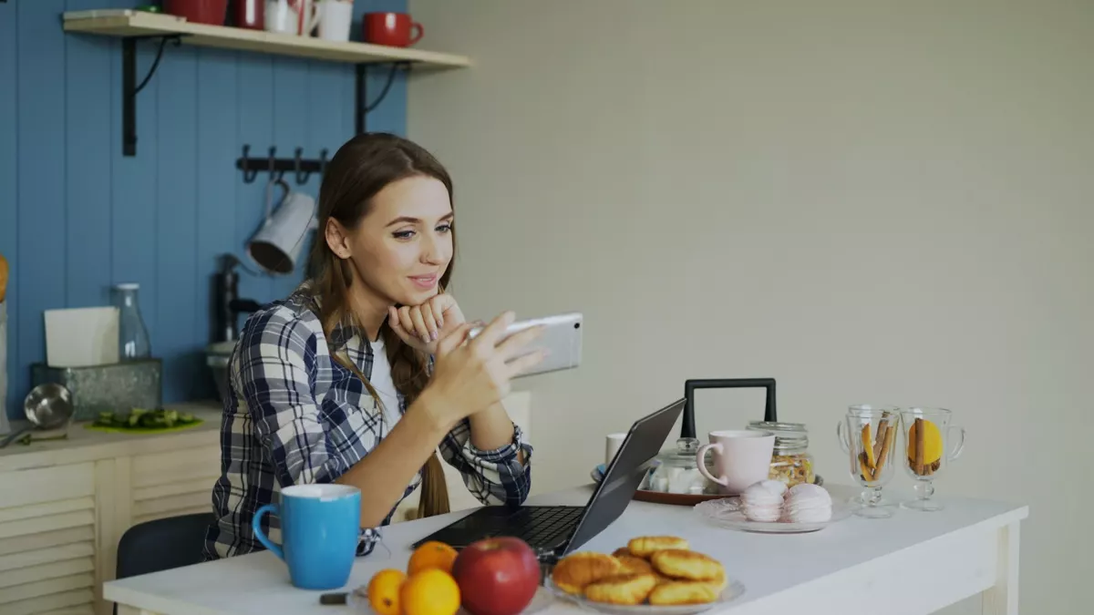 Mutfak masasında akıllı telefonla görüntülü görüşme yapan kadın (temsili görsel)